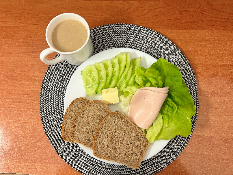 Na zdjęciu: Kawa z mlekiem, Chleb Graham, Masło extra 82%, Blok drobiowy- wędlina drobiowa parzona, Ogórek świeży, Sałata zielona